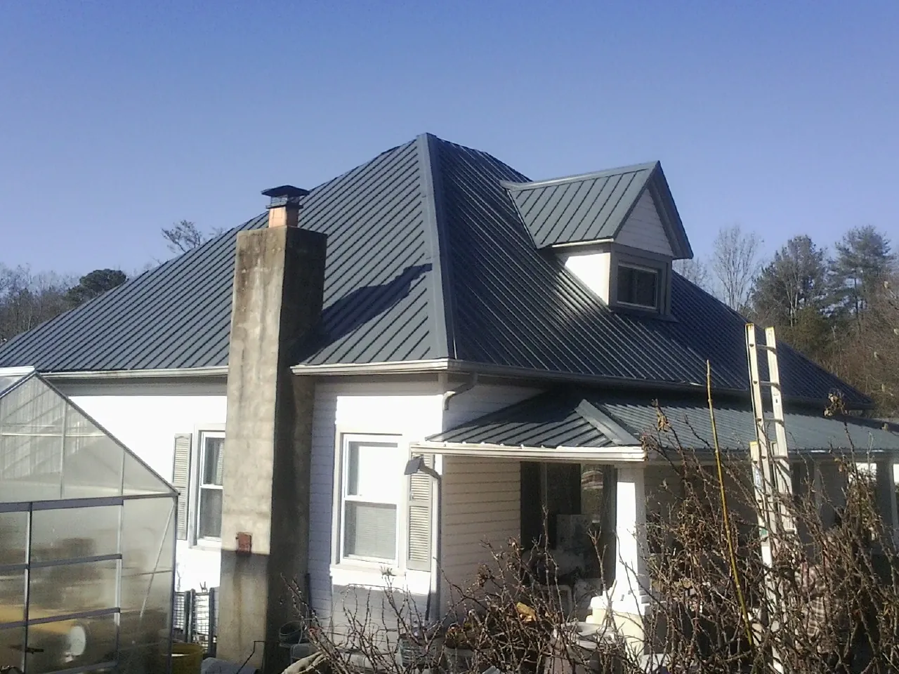 Dark blue standing seam metal roof on a white farmhouse with dormer — Slate & Tile Roof Repair by Roofing Brothers in Buckeye Lake