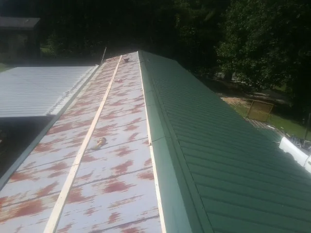 Old rusted panels beside newly installed green metal roofing — Wind Damage Roof Repair by Roofing Brothers in Buckeye Lake