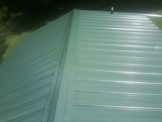 New green metal panels meeting at the ridge of a roof — Flat Roof Repair work by our crew in Buckeye Lake