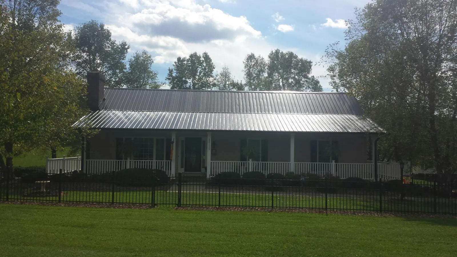 Gray metal roof on a brick ranch with a full width front porch — Gutter Guard Installation work by our crew in Buckeye Lake