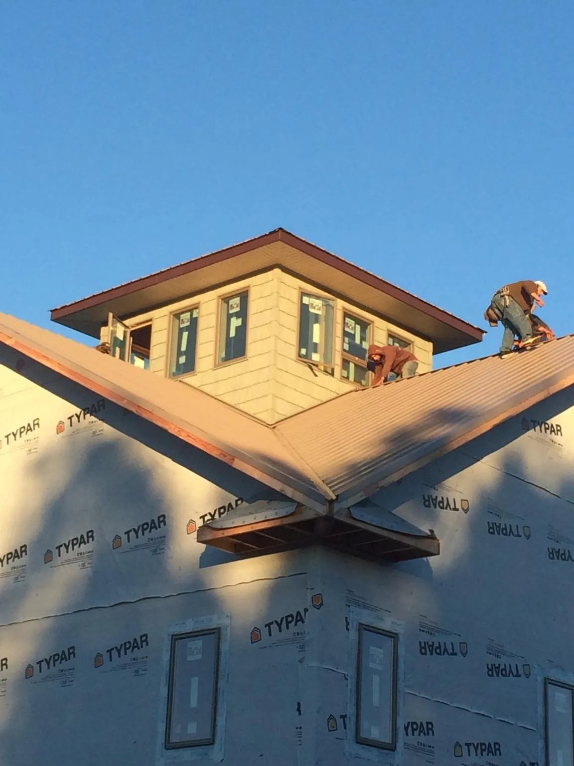 Roofers working around a rooftop cupola on a new metal roof at sunset — Roof Waterproofing in Buckeye Lake by Roofing Brothers